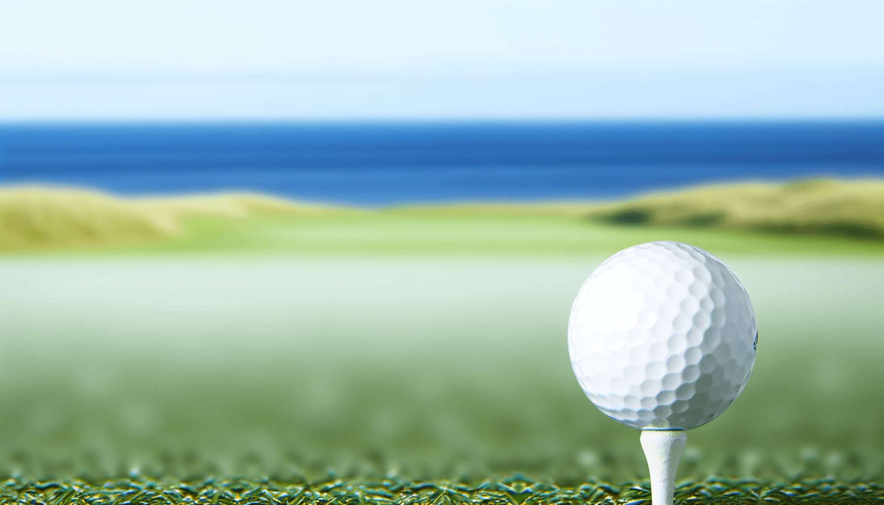 Golf ball on tee with ocean in background
